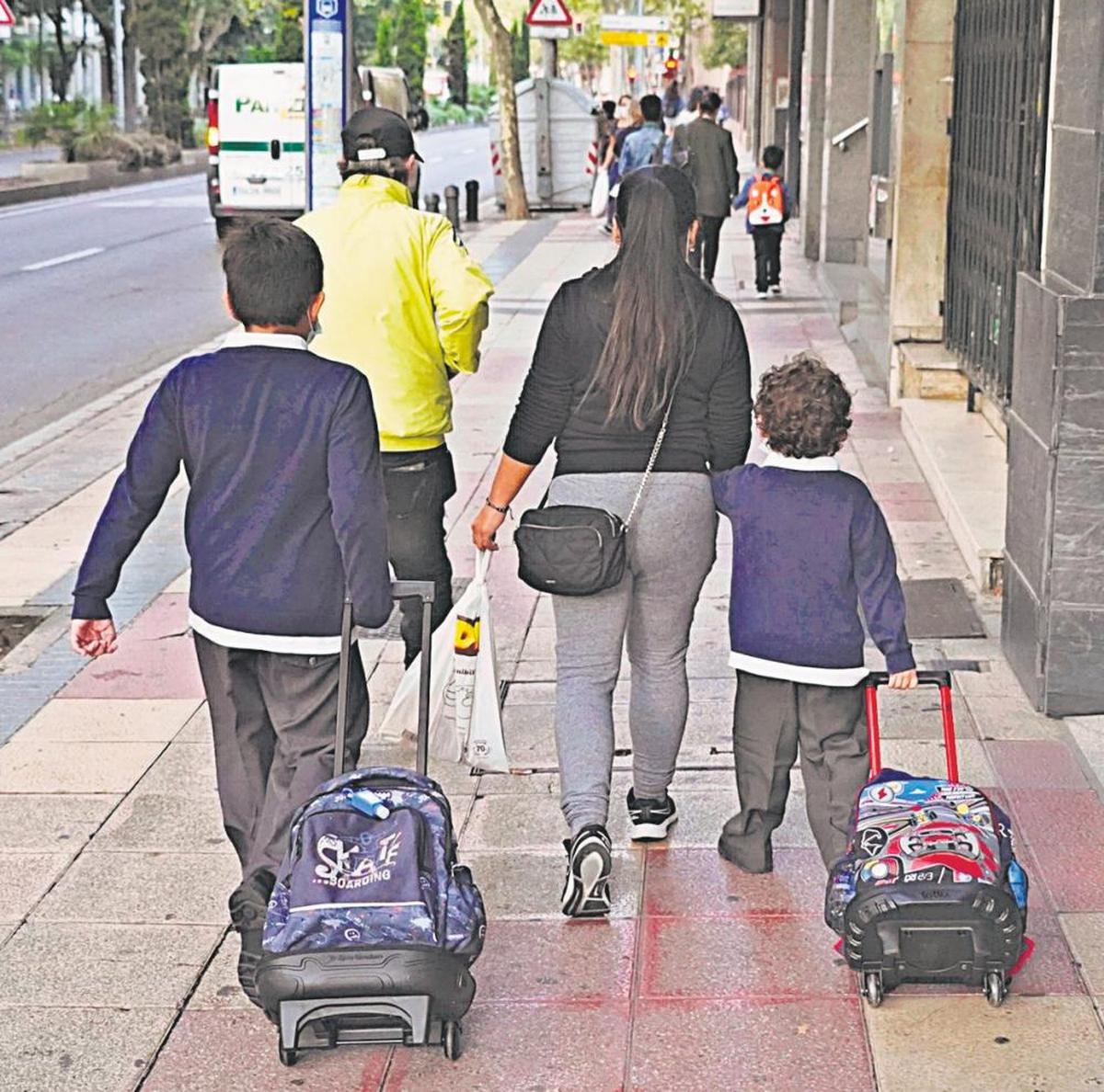 Dos niños se dirigen junto a sus padres al colegio el primer día del curso escolar anterior