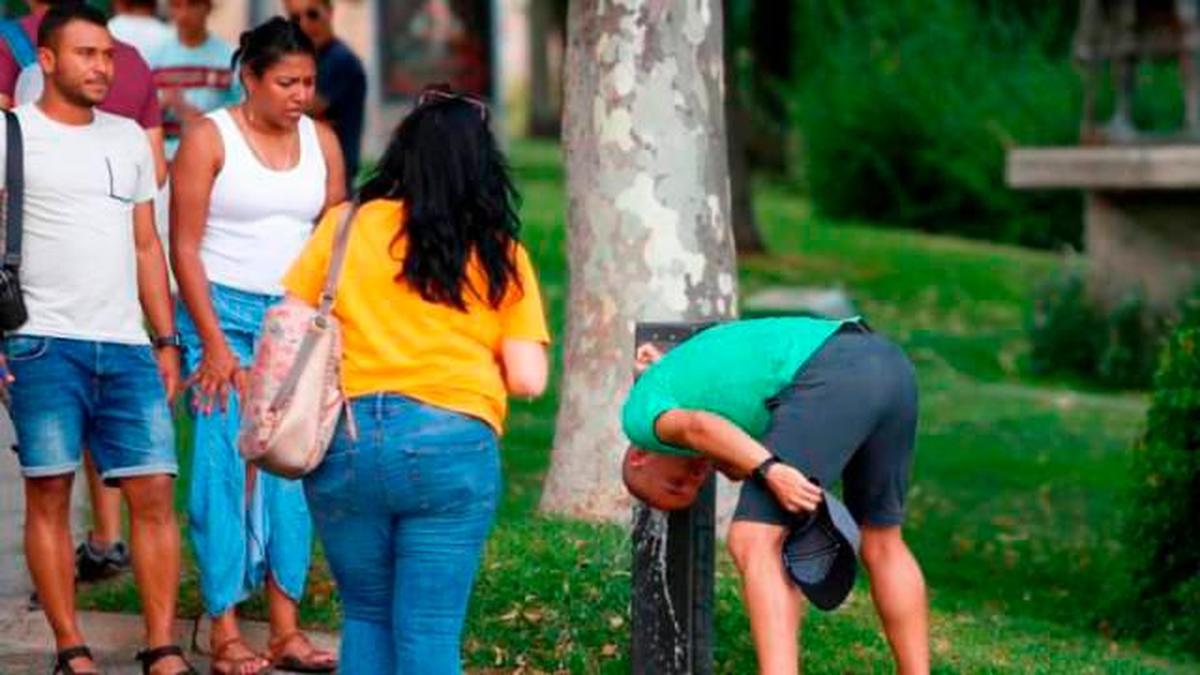 Personas acudiendo a una fuente a refrescarse.