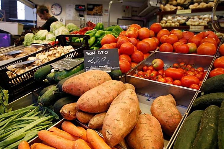 Tomates y boniato junto a más verduras de una frutería.