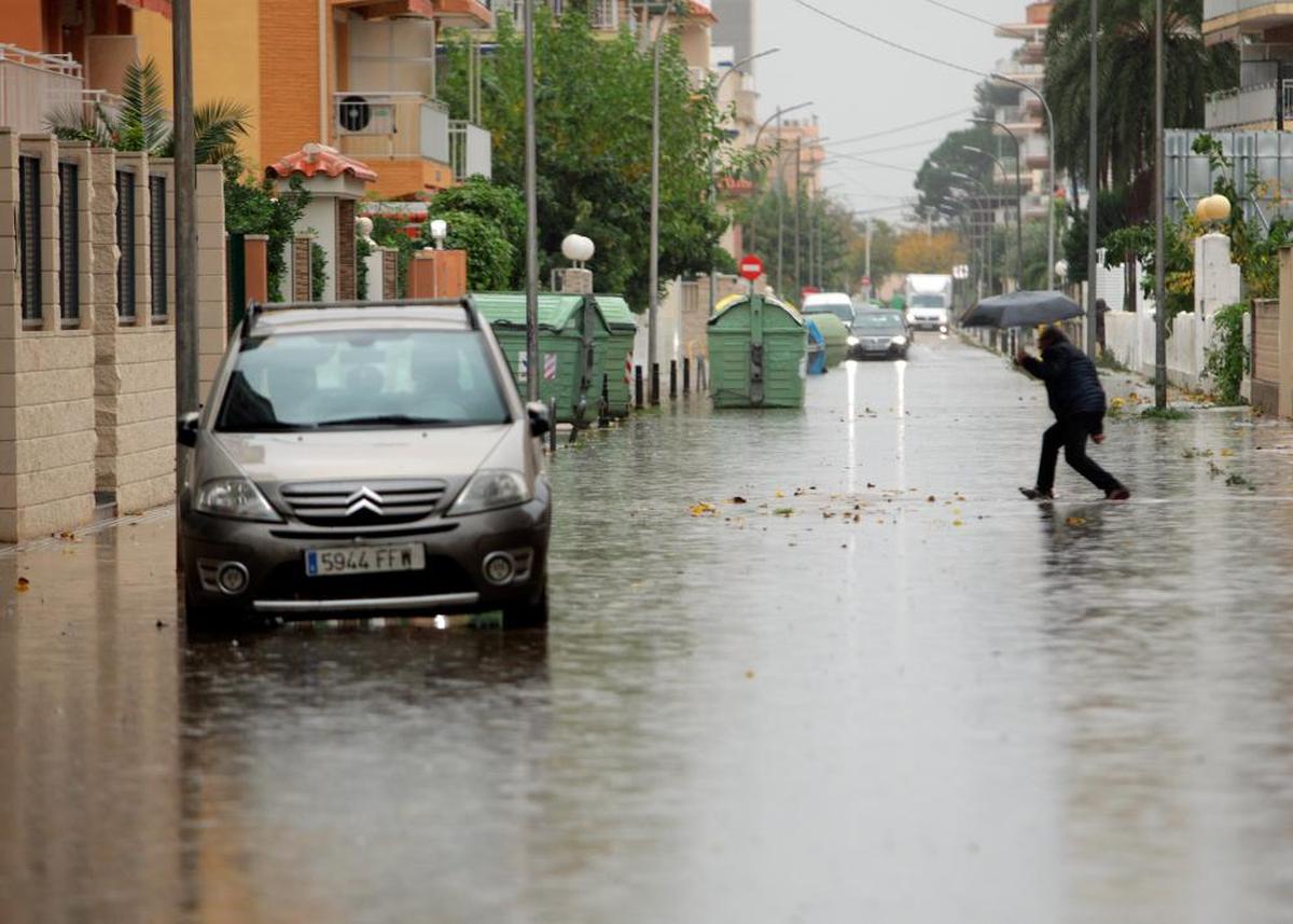 Un hombre cruza la calle bajo una tormenta de agua y granizo.