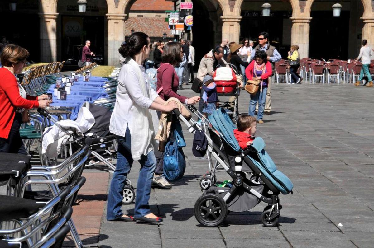 Grupo de madres de paseo por la Plaza Mayor acompañadas de sus hijos en carrito.