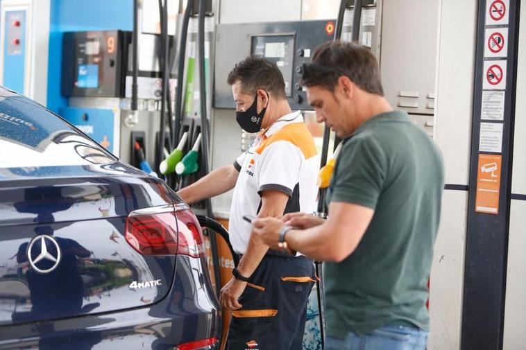 El trabajador de una gasolinera llena el depósito de un turismo