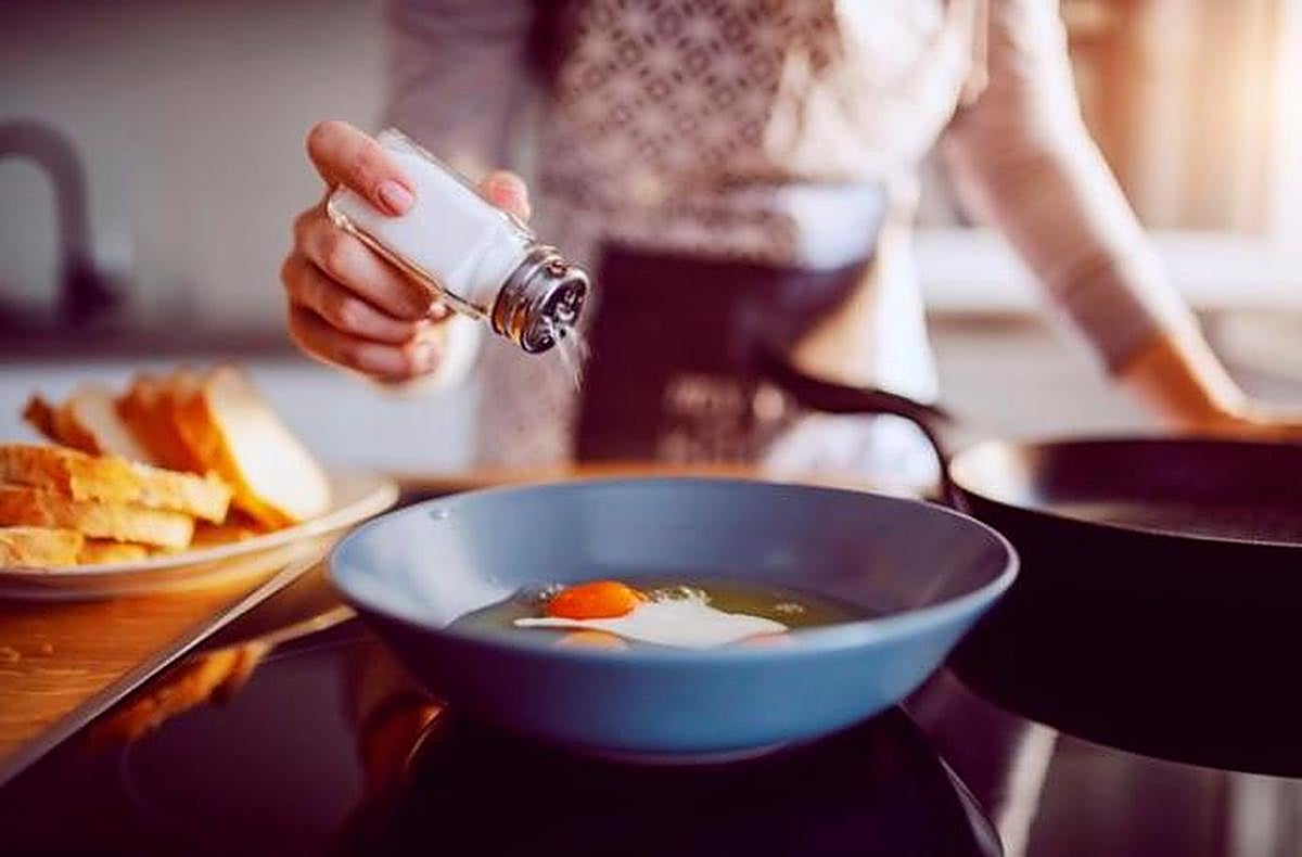 Echando sal a un huevo frito