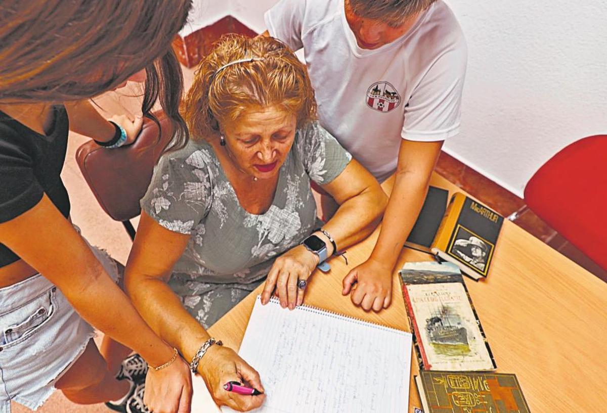 Una abuela escribiendo un relato junto a sus nietos para el certamen.