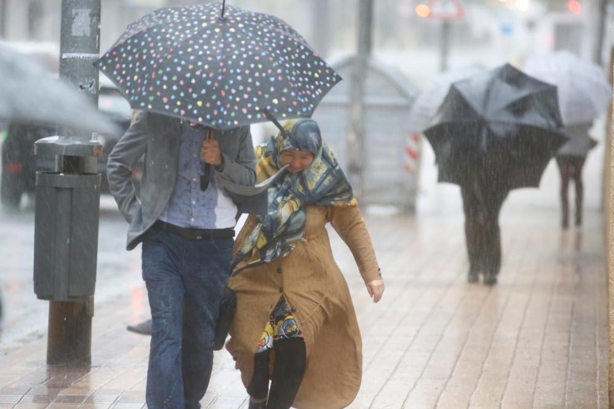 Una pareja se protege del viento y la lluvia ayer en el centro de Salamanca capital. ALMEIDA