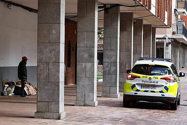 Un coche de la Policía Local en la Plaza Barcelona pasando por delante de una persona sintecho. ALMEIDA