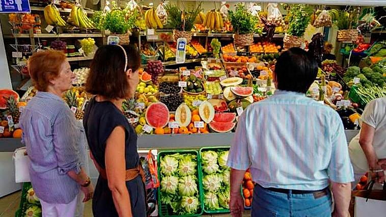 Varios clientes hacen cola en una frutería del mercado