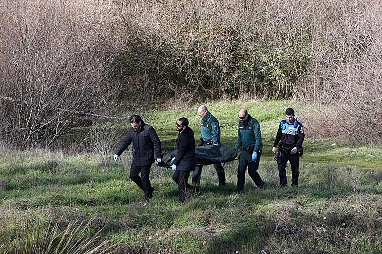 El cadáver del anciano es llevado al furgón funerario.