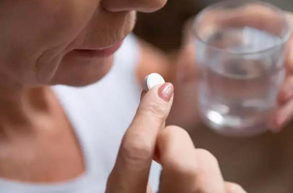 Una mujer toma una pastilla