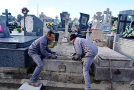 Dos trabajadores del cementerio San Carlos Borromeo desplazando una lápida que se encuentra muy deteriorada. LAYA