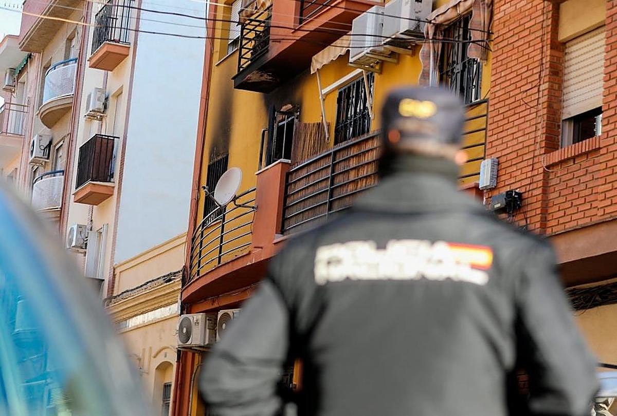 Un agente de Policía Nacional miran en dirección a la vivienda que ha sufrido el incendio en Huelva