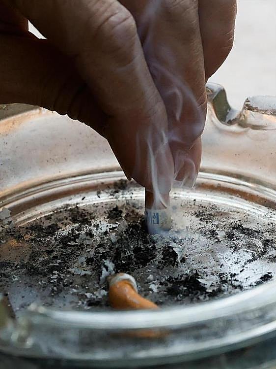 Una persona apaga un cigarrillo en un cenicero.