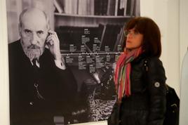 Una visitante recorre la exposición mientras que al fondo se observa la línea vital de Ramón y Cajal.