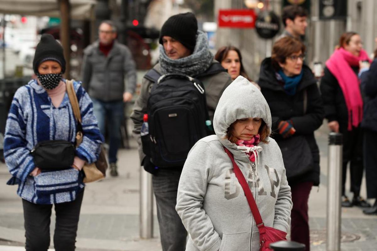 Personas caminana por la calle muy abrigadas por el frío.