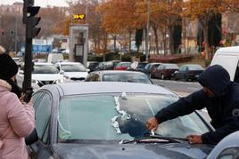 Un individuo tiene que retirar el hielo de su coche.