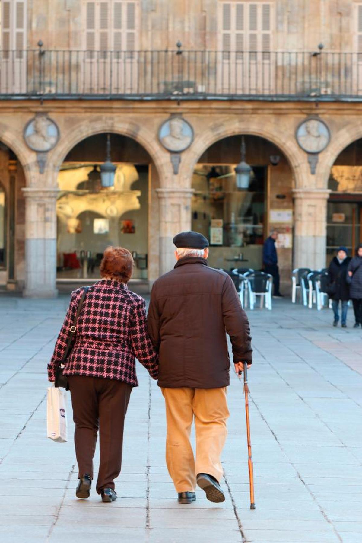 Una pareja de ancianos camina por la Plaza Mayor de Salamanca.