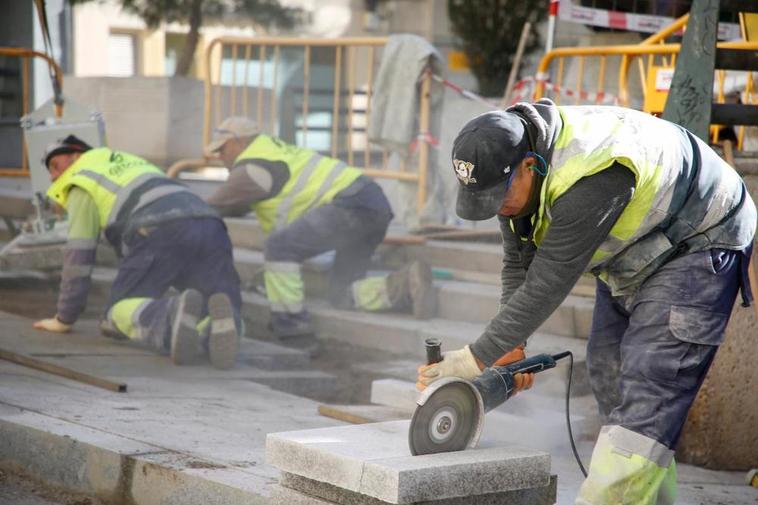 Tres empleados de la construcción trabajando en la reforma urbanística de una calle del centro de la ciudad