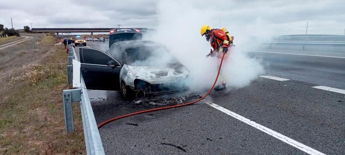 Un bombero intenta sofocar el fuego en un coche en Buenavista