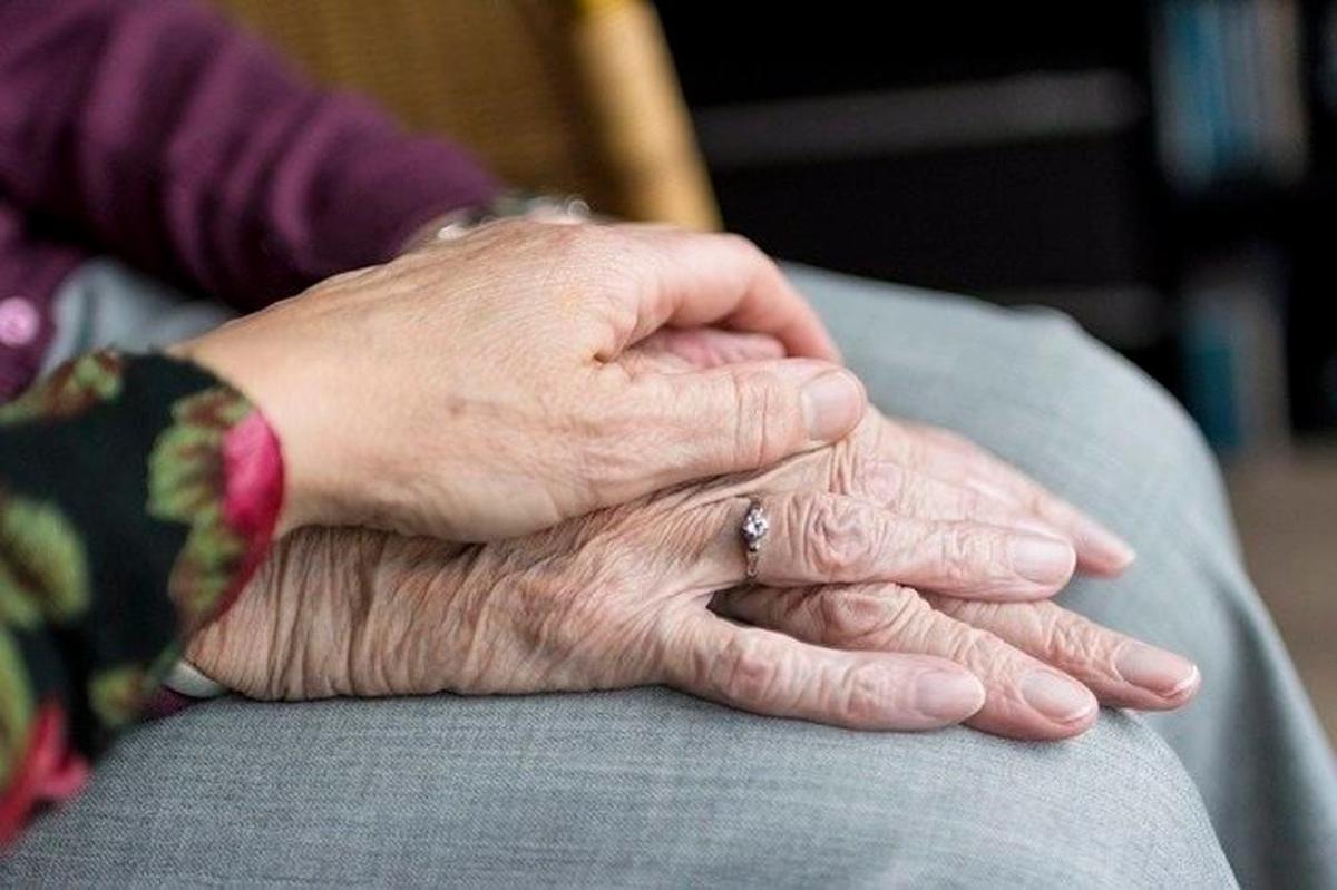 Una mujer agarra la mano de una persona con Alzheimer.