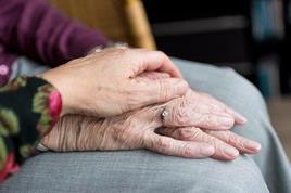 Una mujer agarra la mano de una persona con Alzheimer.