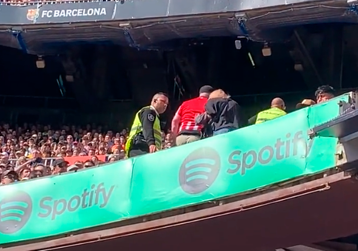 Los miembros del equipo de seguridad del Camp Nou desalojan al aficionado colchonero.