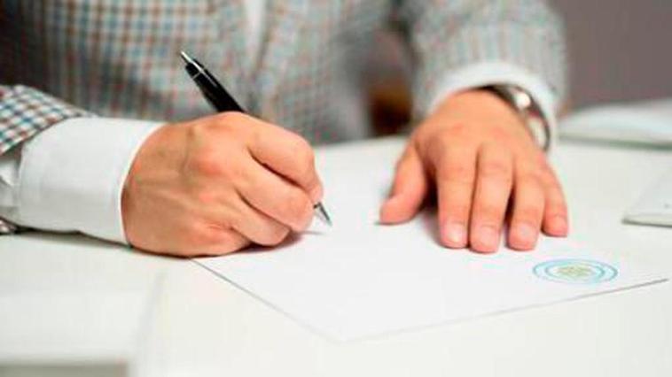 Una persona firma uno documentos con un bolígrafo.