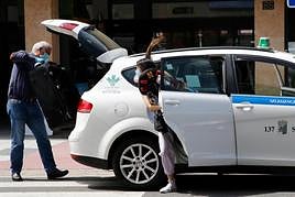 Un taxista ayuda a unos clientes a meter su equipaje en el maletero.