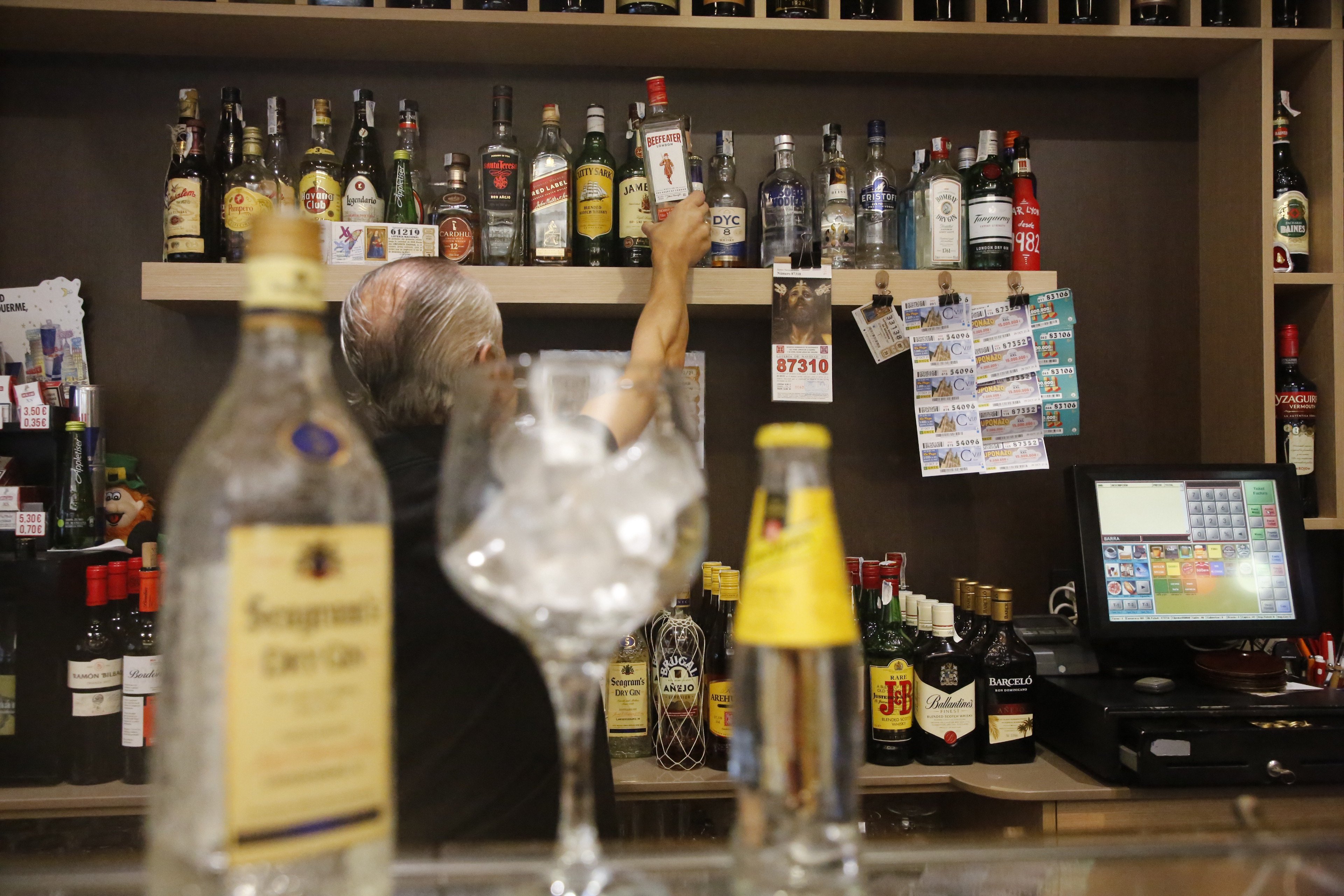 Un camarero coge una botella de ginebra de importación en un establecimiento salmantino.