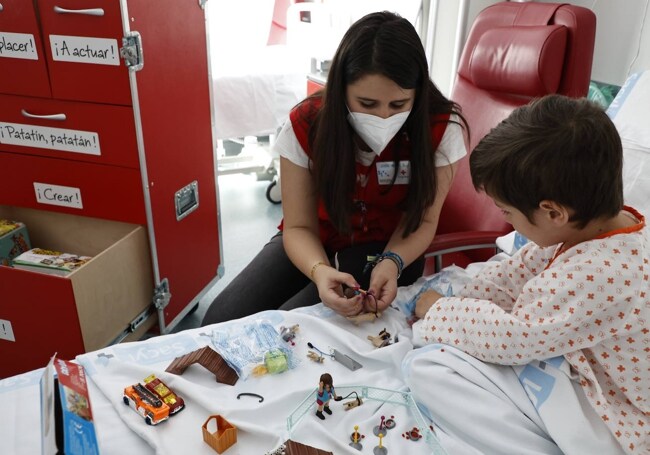 Una de las voluntarias de Cruz Roja Juventud, Berta Collazos, jugando con un niño hospitalizado.