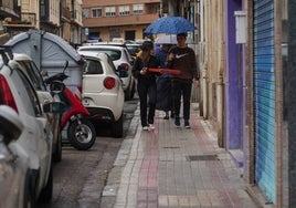 Una pareja camina bajo un paraguas por la calle Melchor Cano.