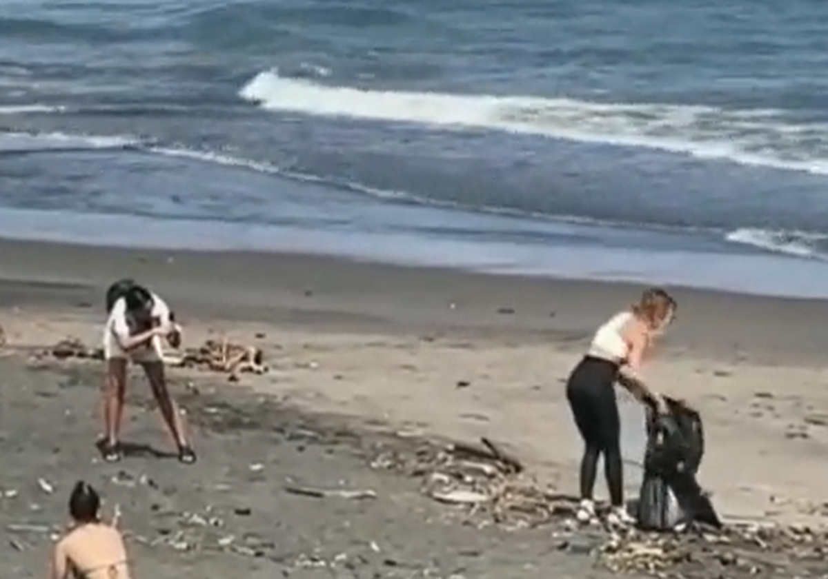 Influencer siendo grabada mientras recoge la basura de la playa