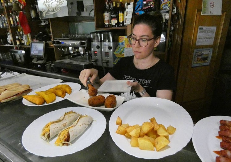 Camarera sirviendo una croqueta en un bar de Cantalapiedra