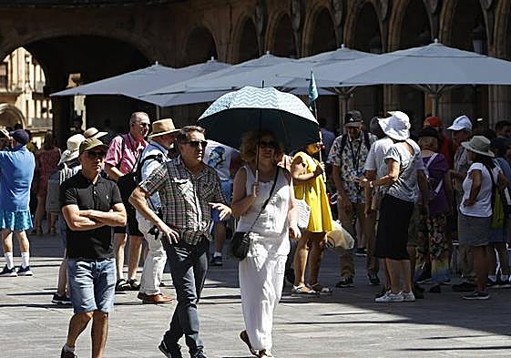 Varios turistas se refugian bajo los paraguas durante la tarde de este martes en Salamanca.