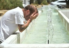 Un hombre se refresca en una fuente.