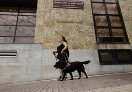 La joven invidente Claudia Iturregui con Miel, su perra guía, por la fachada de la Facultad de Derecho.