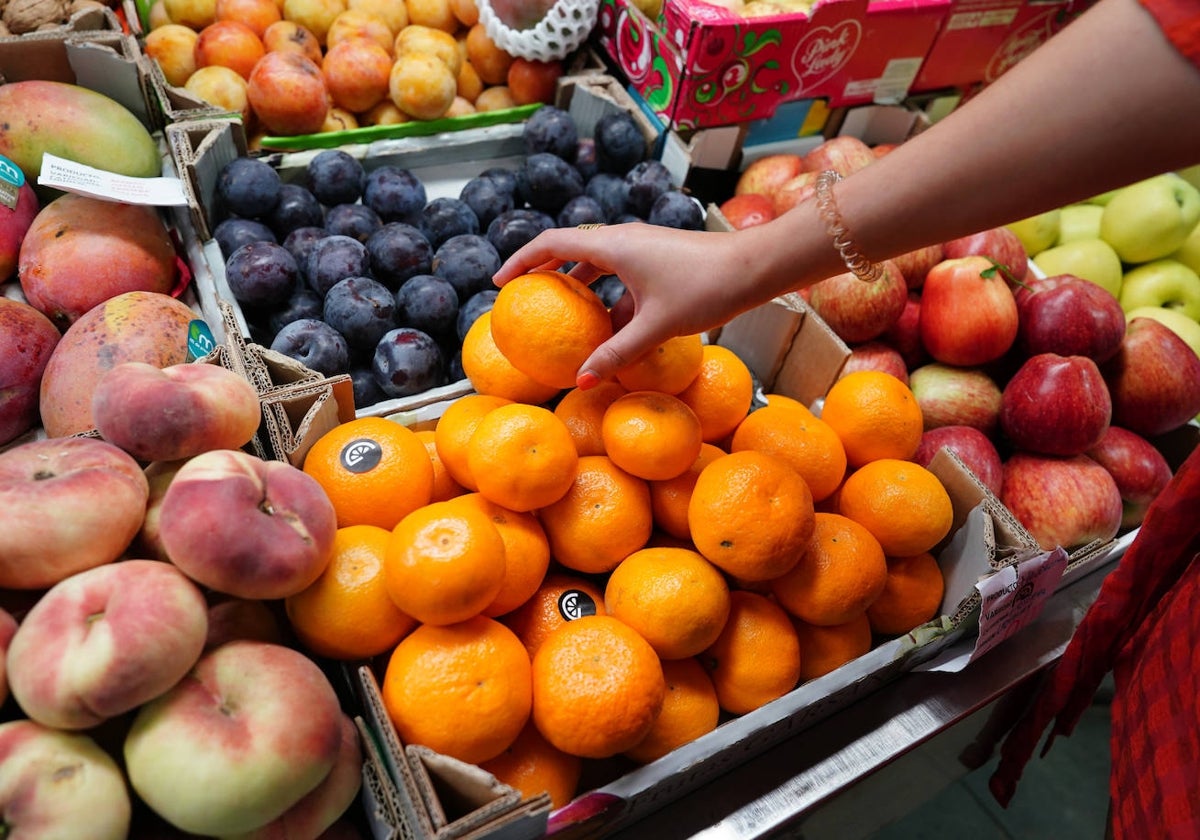 Una mujer coge mandarinas en una frutería de Salamanca.