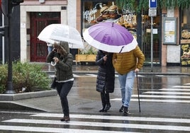 Un grupo de salmantinos cruza un paso de peatones bajo la lluvia.