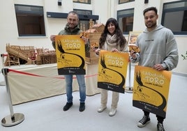 Rubén Benito, Paola Martín y Víctor Gómez con los carteles y pegatinas del Carnaval del Toro 2024.