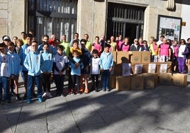 Parte de los asistentes que acudieron al entrenamiento solidario junto a los alimentos recaudados