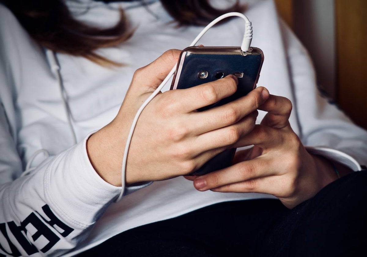 Una joven consulta su teléfono móvil.