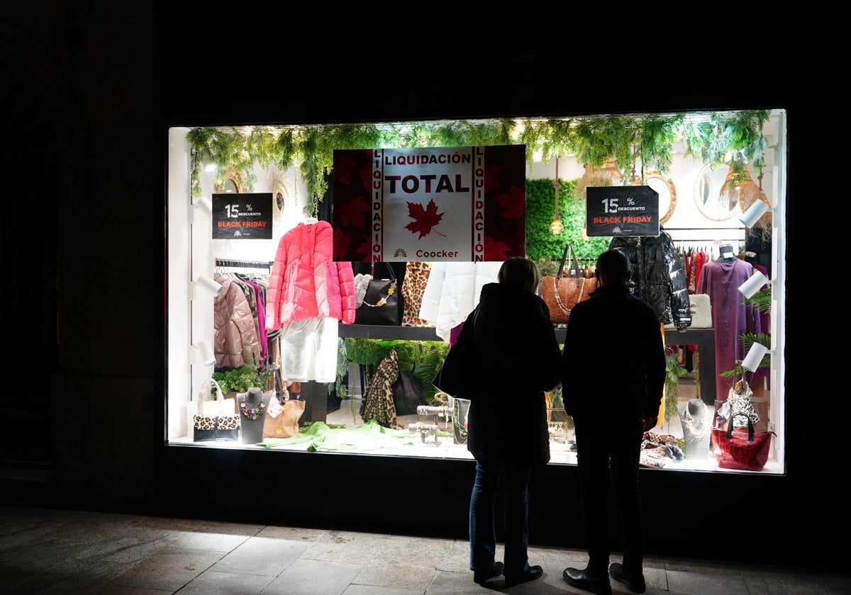 Dos personas miran una tienda iluminada tras el fin de la medida.