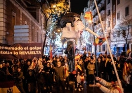 Un hombre apalea un muñeco de Pedro Sánchez frente a la sede del PSOE en la calle Ferraz