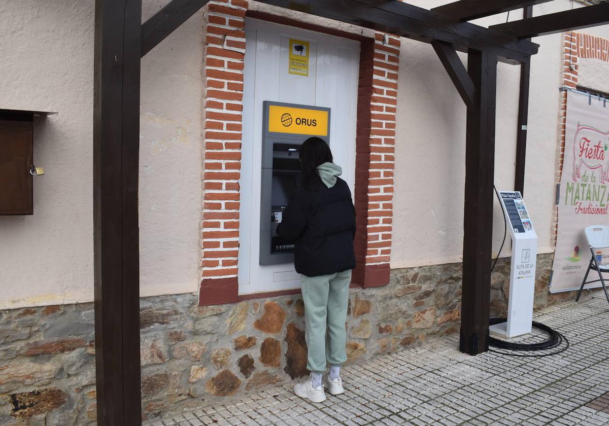 Una vecina utilizando el cajero automático de Galinduste, situado en la plaza.