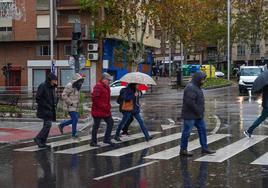 Peatones salmantinos caminan con parguas y capuchas para resguardarse de la lluvia