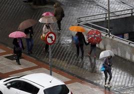 Varias personas paseando por la calle en un día de lluvia.