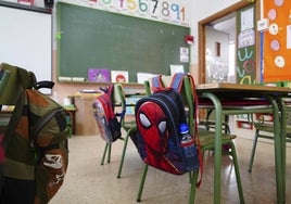 Mochilas colgados en las sillas de un aula.