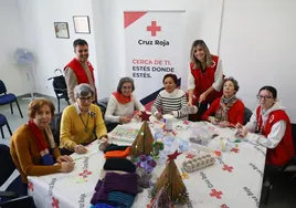 Integrantes del taller de manualidades de Cruz Roja junto a voluntarios y sus trabajos.