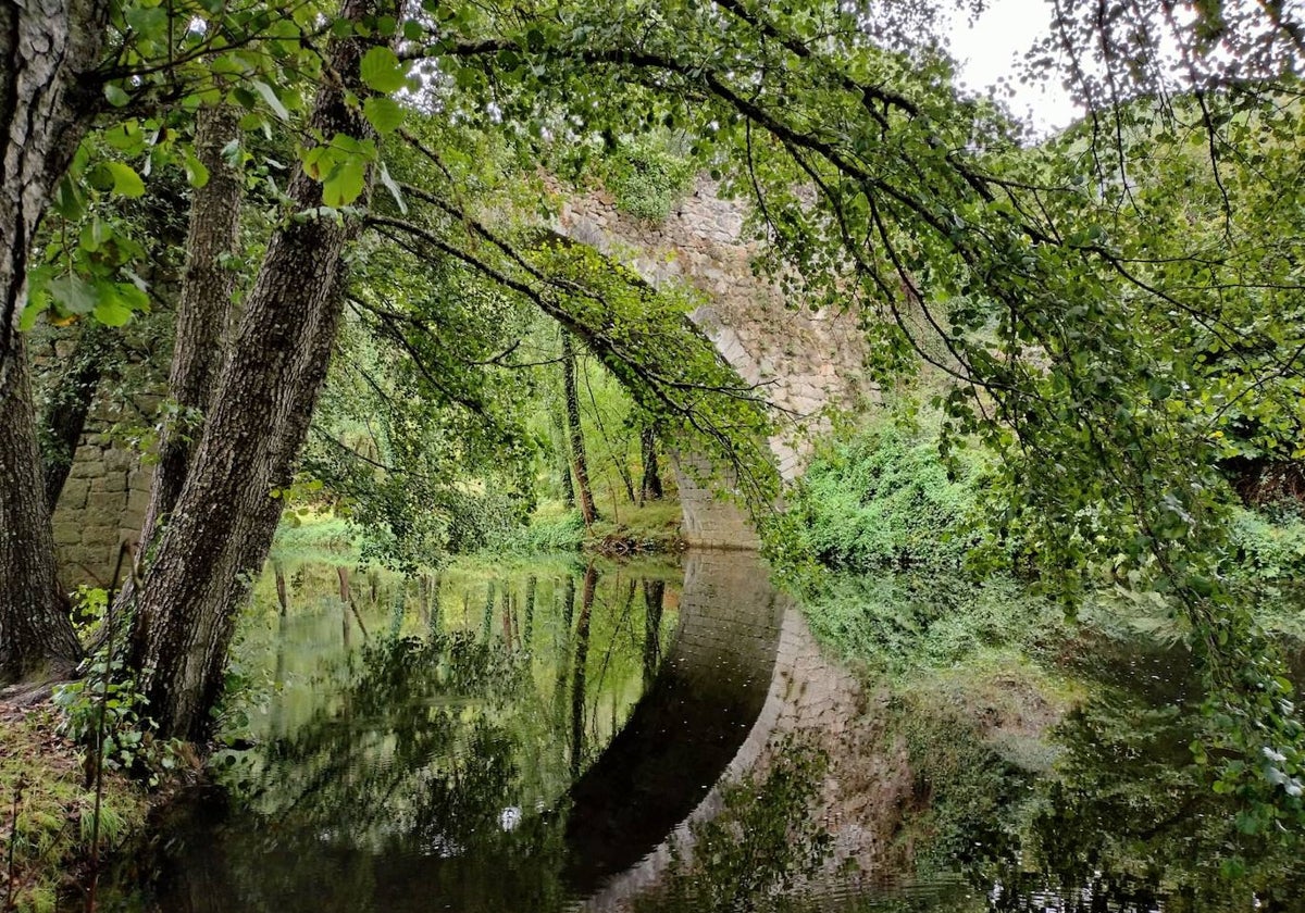 Imagen del puente medieval sobre el río Cuerpo de Hombre rodeado de naturaleza.