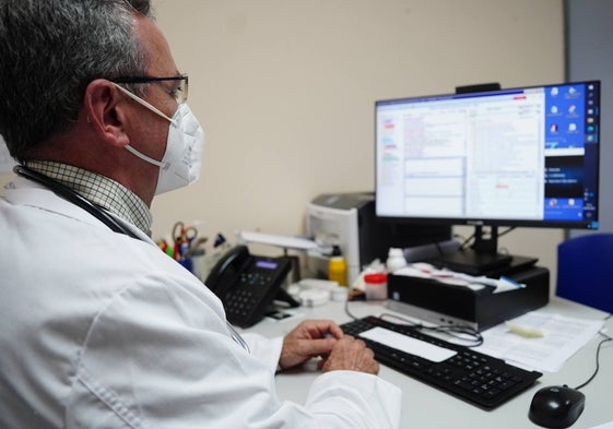 Un médico de familia, frente al ordenador de su consulta.