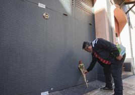 Un hombre deposita una rosa en el garaje de la vivienda donde un hombre ha matado presuntamente a su mujer y sus dos hijos menores